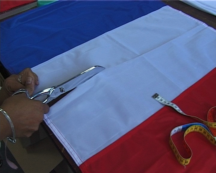 photo extraite d'une video, des mains tenant un ciseau coupent le drapeau tricolore